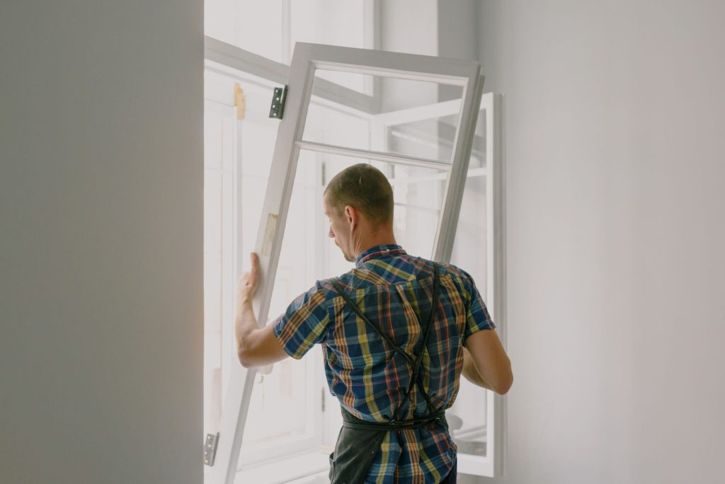 Professionnel posant un vitrage isolant dans le cadre d’une fenêtre