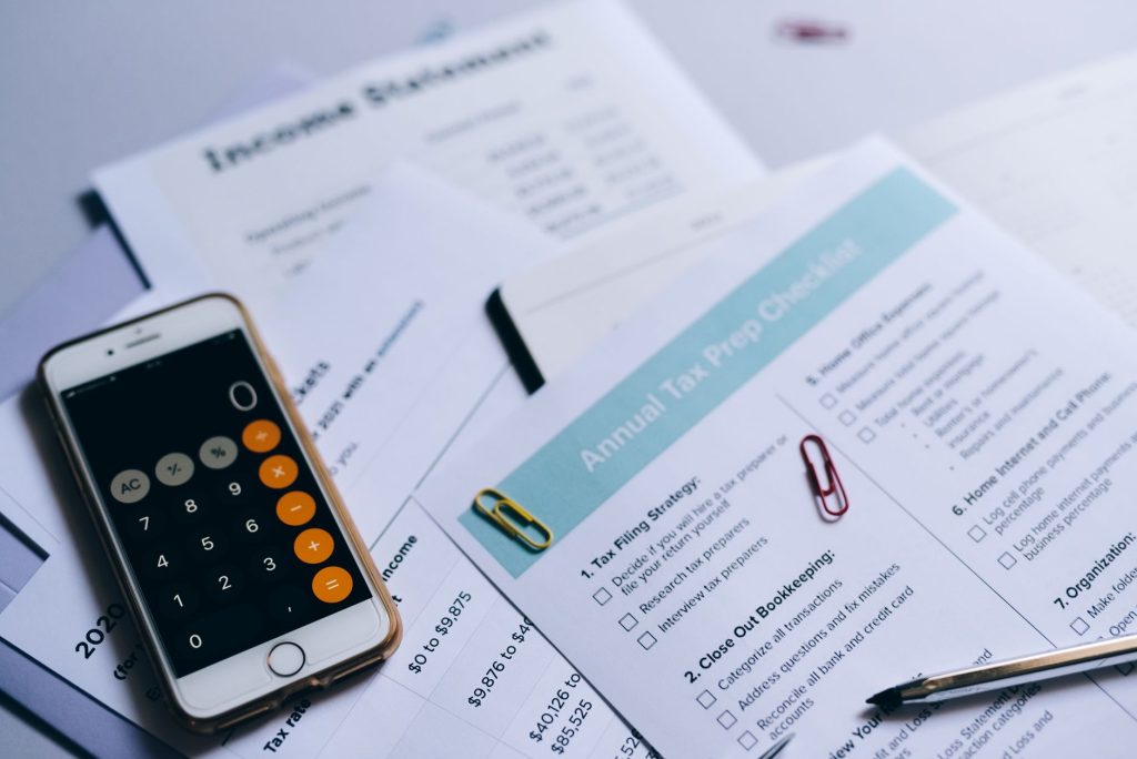 Calculatrice, billets et documents fiscaux posés sur un bureau pour estimer la taxe foncière