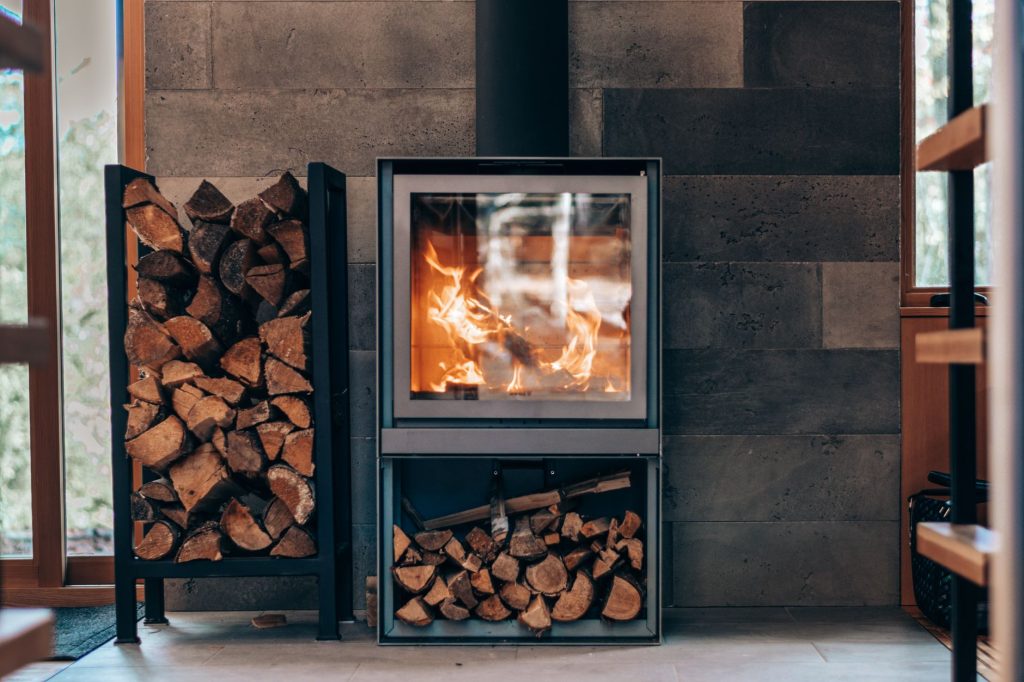 Poêle à bois moderne avec une flamme et des bûches dans un salon